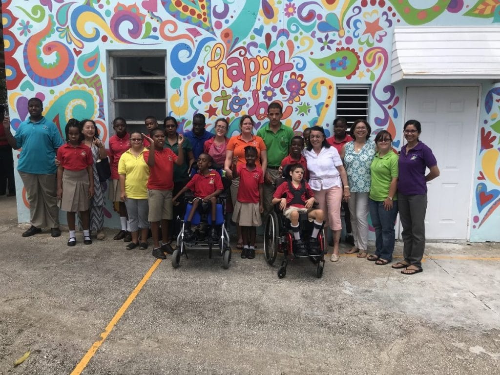 Group picture of people in front of a colourful painted house wall