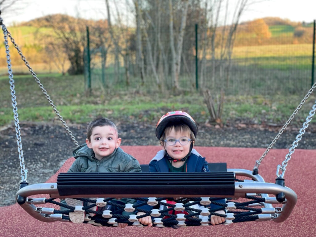 2 Kinder auf neuer Hängematte auf inklusivem Spielplatz