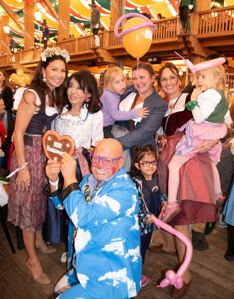 Regine Sixt und Noni Sixt mit Kindern und Betreuerinnen und einem Clown im Schützenfestzelt auf Regines Kinderwiesn